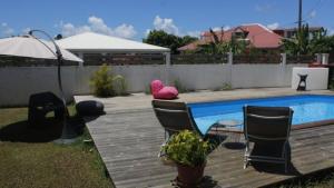 a pink teddy bear sitting on a deck next to a swimming pool at Studio accueillant à Baie Mahault, 22 m², piscine partagée. in Baie-Mahault