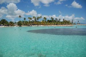 a beach with a small island in the water at Studio accueillant à Baie Mahault, 22 m², piscine partagée. in Baie-Mahault