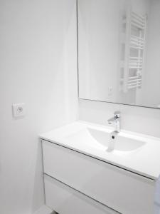 a white bathroom with a sink and a mirror at Appartement lumineux à Saint-Cyprien 45 m² vue mer in Saint-Cyprien +9 photos