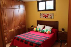 a bedroom with a red bed with a plaid blanket at Cosy chalet with panoramic views in Icod de los Vinos - 70m² in Icod de los Vinos