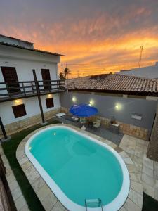 a pool in front of a house with a sunset at Convés Pousada in Barra de São Miguel +35 photos