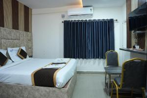 a bedroom with a bed and a chair and a window at Hotel Sai Capital in Vijayawāda