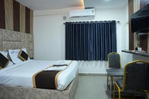 a bedroom with a bed and a table and a chair at Hotel Sai Capital in Vijayawāda +21 photos