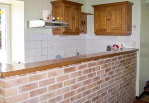 a kitchen with a brick counter and wooden cabinets at Maison accueillante à La Chapelle-aux-Choux avec jardin spacieux 70 m² in La Chapelle-aux-Choux