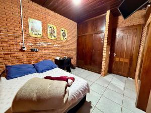 a bedroom with a bed and a brick wall at Quarto com Banheiro Privado no Centro de Botucatu in Botucatu