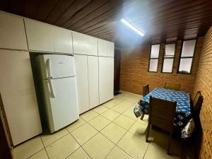 a kitchen with a table and a refrigerator in it at Quarto com Banheiro Privado no Centro de Botucatu in Botucatu