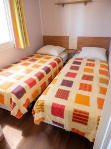 two beds sitting next to each other in a room at Bungalow charmant à Rochechouart avec vue sur lac in Rochechouart