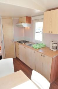 a kitchen with wooden cabinets and a sink and a window at Bungalow charmant à Rochechouart avec vue sur lac in Rochechouart