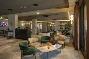 a restaurant with green chairs and tables in a lobby at Continental Golf Resort in Verbania