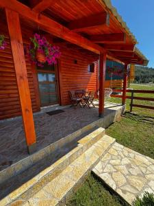 a porch of a log cabin with a table and flowers at Hanovi Apartments in Borje