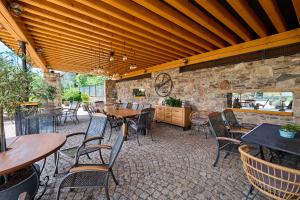 a patio with tables and chairs and a stone wall at Apartmány Wake up Coffee in Proseč