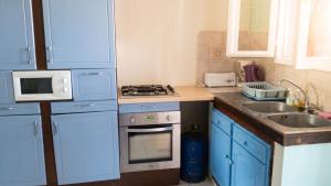 a small kitchen with blue cabinets and a sink at Maison confortable Le Moule Jacuzzi in Le Moule