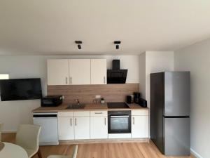 a kitchen with white cabinets and a black refrigerator at Apartment Itzehoe in Itzehoe