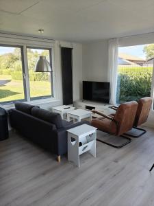 a living room with a couch and chairs and a tv at Luxe 6 persoons bungalow met 3 slaapkamers 2 badkamers en ensuite ligbad in Sint Maartensvlotbrug
