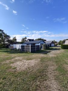 a fence in a field with houses in the background at Luxe 6 persoons bungalow met 3 slaapkamers 2 badkamers en ensuite ligbad in Sint Maartensvlotbrug