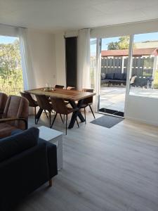 a living room with a table and a couch at Luxe 6 persoons bungalow met 3 slaapkamers 2 badkamers en ensuite ligbad in Sint Maartensvlotbrug