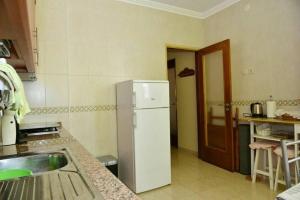 a kitchen with a white refrigerator and a sink at Comfortable apartment with lake view in Vila Real - 75m² in Vila Real de Santo António