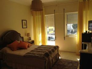 a bedroom with a bed with orange pillows and a window at Comfortable apartment with lake view in Vila Real - 75m² in Vila Real de Santo António