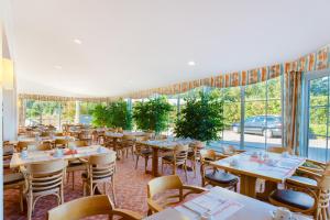 ein Restaurant mit Tischen, Stühlen und Fenstern in der Unterkunft Hotel Montana Lauenau in Lauenau