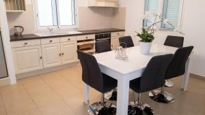 a kitchen with a white table and black chairs at Villa enchanteresse à Saint-Benoît avec piscine privée in Saint-Benoît