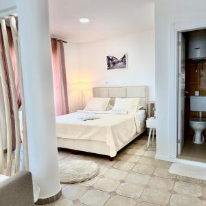 a white bedroom with a bed and a bathroom at Villa Guci in Ulcinj