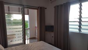 a bedroom with a bed and a window with a television at Comfortable apartment in Baie Sainte Anne 56 m² with sea view in Baie Sainte Anne