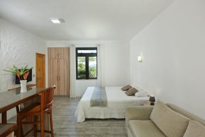 a white bedroom with a bed and a couch at Charming studio in Moka 40 m² with mountain view terrace in Moka