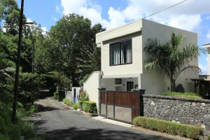 a white house with a fence and a stone wall at Charming studio in Moka 40 m² with mountain view terrace in Moka +2 photos