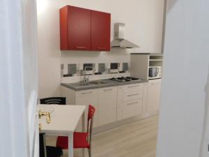 a white kitchen with red cabinets and a table at Contemporary Apartment in Trapani, 50 m² with Balcony in Trapani