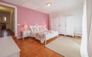 a bedroom with a white bed and pink walls at Spacious House in Can Trabal in Can Trabal
