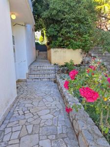 a stone walkway next to a building with pink roses at Adrasteja 3 - apartment Dramalj in Dramalj