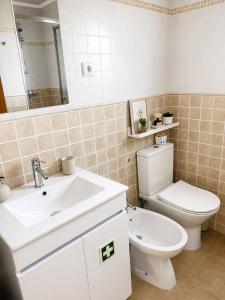 a bathroom with a white toilet and a sink at Casa da Maré in Calheta +28 photos