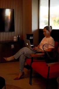 a woman sitting on a chair with a laptop at Hotel Tupinambá Timon in Timon