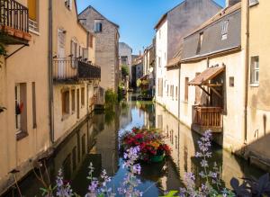 a canal between two buildings with flowers on it at Studio cosy à Montargis - 13 m² - Parking inclus in Montargis +18 photos