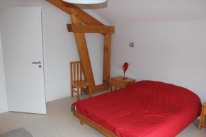 a bedroom with a red bed and a chair at Appartement accueillant à Xonrupt-Longemer 70 m² avec jardin privatif in Xonrupt-Longemer