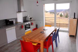 a kitchen with a wooden table and red chairs at Appartement accueillant à Xonrupt-Longemer 70 m² avec jardin privatif in Xonrupt-Longemer