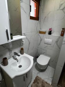 a white bathroom with a sink and a toilet at Hanovi Apartments in Borje +20 photos