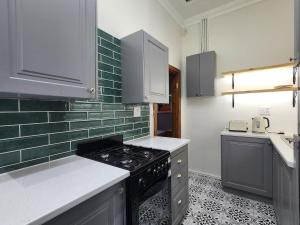 a kitchen with white cabinets and a stove top oven at GreenMarket Apartment in Knysna +2 photos