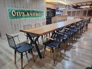 a long wooden table and chairs in a room at Hotel Opalchenets Стаи за гости и парти зала in Shipka
