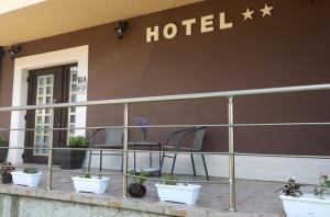 a hotel sign on the side of a building with plants at Hotel Opalchenets Стаи за гости и парти зала in Shipka