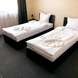 two beds in a hotel room with white sheets at Hotel Opalchenets Стаи за гости и парти зала in Shipka