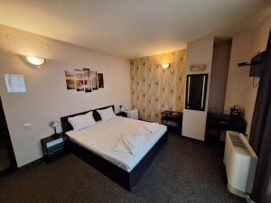 a hotel room with a bed with two towels on it at Hotel Opalchenets Стаи за гости и парти зала in Shipka