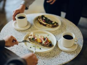 ein Tisch mit zwei Tellern Essen und zwei Tassen Kaffee in der Unterkunft Arbor Onomichi in Onomichi