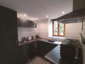 a kitchen with black cabinets and a sink and a stove at Kinvara Gite in Dournazac