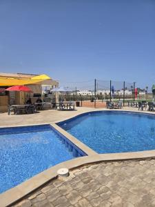 a large swimming pool next to a patio with tables and chairs at Mini villa 1 Al hoceima in Al Hoceïma