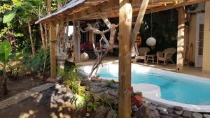 a swimming pool in a backyard with a wooden pergola at Appartement moderne à Le Lamentin avec piscine partagée - 20m² in Le Lamentin