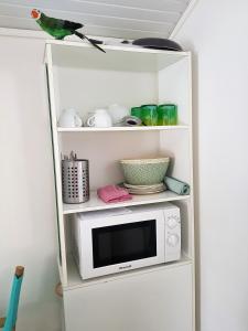a white shelf with a microwave on top of it at Appartement moderne à Le Lamentin avec piscine partagée - 20m² in Le Lamentin +20 photos