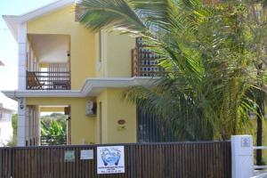 a yellow house with a fence and a palm tree at Modern Apartment in Pereybere + Pool in Pereybere