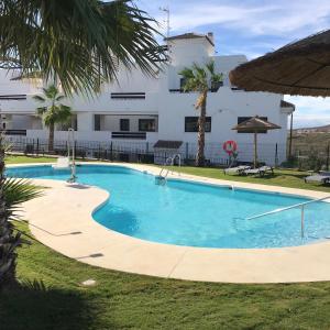 a swimming pool in front of a building at Spacious Apartment with Views in Málaga, 77 m², Shared Pool in San Luis de Sabinillas