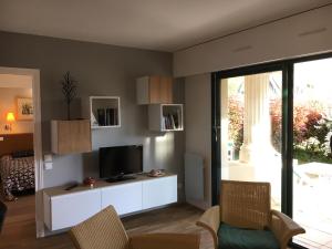 a living room with a tv on a white cabinet at Appartement cosy à Saint-André-des-Eaux de 47 m² avec jardin in Saint-André-des-Eaux